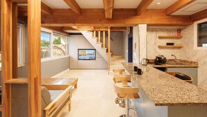 A modern kitchen with a wooden staircase, a TV, and a kitchen island. - Hanok Pension Wanggyeong (Gyeongju)