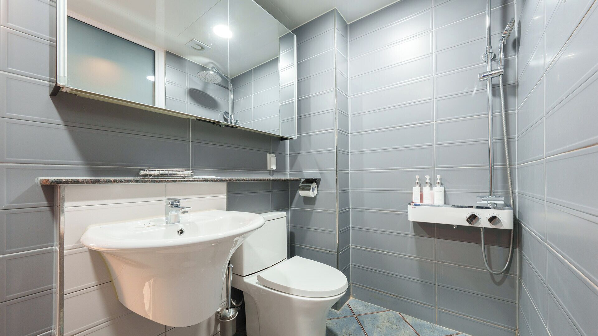A modern bathroom with a white sink, toilet, and shower.