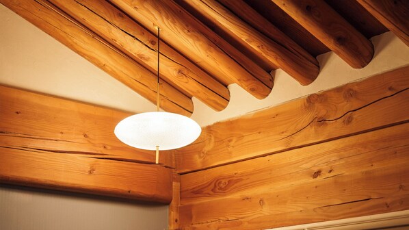 A wooden ceiling with exposed beams and a hanging light fixture.