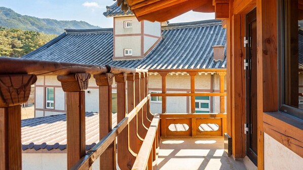 A traditional Japanese building with wooden architecture, a balcony with a wooden railing, and a view of the surrounding landscape. - Hanok Pension Wanggyeong (Gyeongju)
