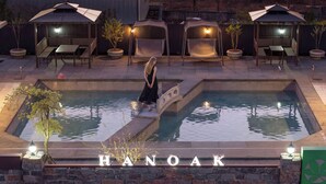 A pool area with lounge chairs and a person standing by the pool. - Hanok Pension Wanggyeong (Gyeongju)