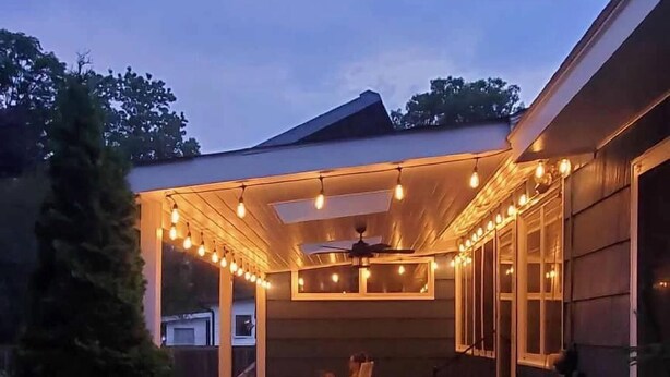 Un patio couvert agrémenté de guirlandes lumineuses, d’un ventilateur de plafond et de différents espaces pour s’asseoir.