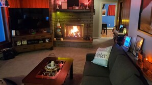 Un salon avec une cheminée, un téléviseur et un canapé agrémenté d’un coussin.