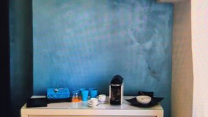 Una kitchenette compacta con nevera incorporada, microondas, un lavamanos pequeño y un estante sobre la encimera.