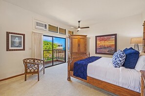 Quarto com cama, cadeira, guarda-roupa, ventoinha no teto e vista para o exterior.