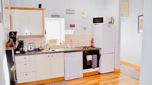 Cozinha compacta com armários brancos, micro-ondas, geladeira e pia.