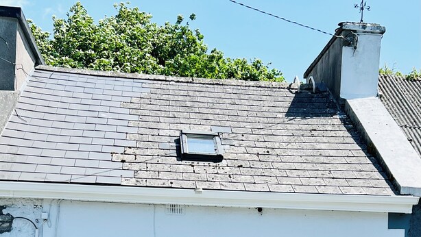 Um edifício branco com telhado telhado, uma porta branca e um banco na parte externa.
