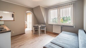 Una habitación moderna y bien iluminada con zona de comedor, sofá y vistas al exterior.
