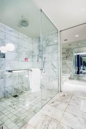 A modern bathroom with marble tiles, a glass shower enclosure, and a visible toilet. - Stunning Strip-view Studio w/ Balcony Access 35308 (Las Vegas)