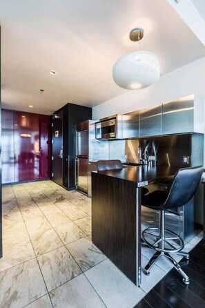 A modern kitchen with a central island, stainless steel appliances, and a bar area. - Stunning Strip-view Studio w/ Balcony Access 35308 (Las Vegas)