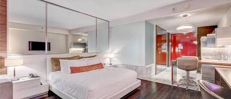 A modern hotel room with a large bed, a desk, and a seating area.
