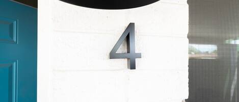 A house number '4' mounted on a white brick wall.