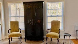 Une pièce comprenant deux fauteuils, un buffet en bois foncé et une petite table.