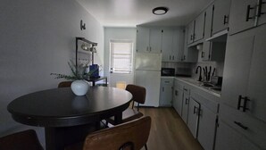 A compact kitchen with white cabinets, a dining table with chairs, and a refrigerator. - Blue&pink#3 Pool Centralphx (Phoenix)