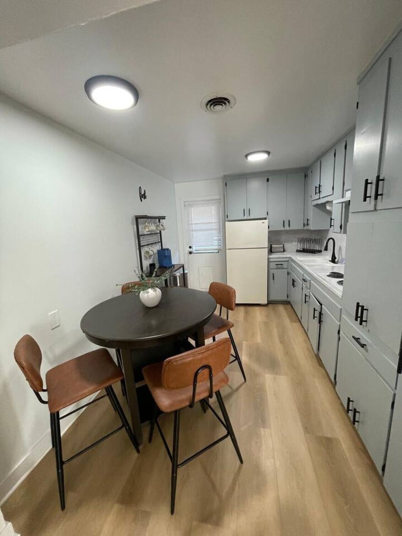 Une cuisine compacte comprenant une table à manger, des chaises et des appareils électroménagers modernes.