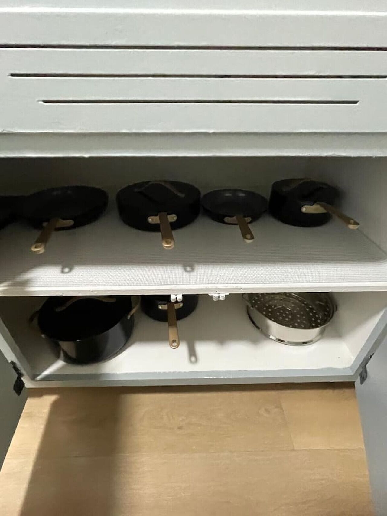 Una cocina con un estante que contiene varias ollas y sartenes.