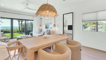 Un espace de repas moderne avec une table en bois, des chaises en osier et une grande fenêtre donnant sur l’extérieur.