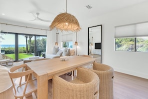 Un comedor moderno con una mesa de madera, sillas de mimbre y una lámpara de techo grande de fibra.