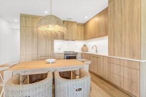 Una cocina moderna con armarios de madera, una isla central y una lámpara colgante.