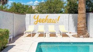 A poolside area with a white wall featuring the text "Yeehaw!" and four yellow lounge chairs. - New! Blue&pink Pool Centra PHX (Phoenix)