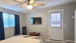A bedroom with a bed, a ceiling fan, a TV, a door, and a window with blinds. - Charming Apt Downtown Phoenix Historic Patio (Phoenix)