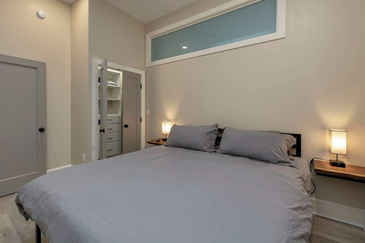 Ein Schlafzimmer mit einem Bett, Nachttischlampen, einem Kleiderschrank und einem Fenster.