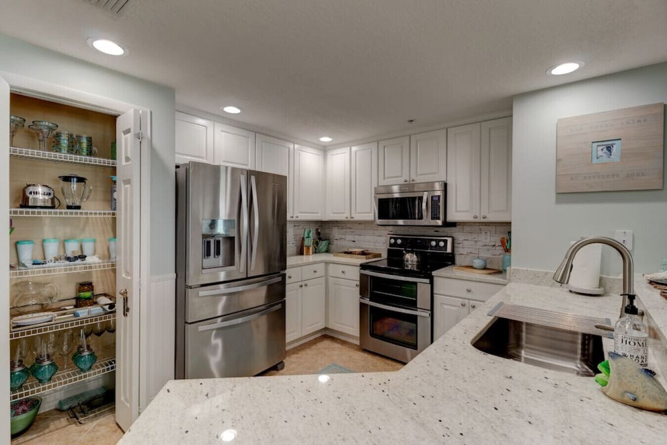 A modern kitchen with white cabinets, stainless steel appliances, and a granite countertop.