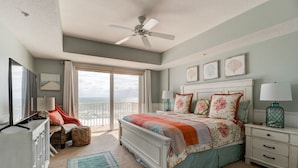 Un dormitorio con cama, mesita de noche, cómoda, silla, ventana con vista y ventilador de techo.