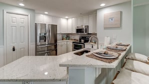 Una cocina moderna con armarios blancos, electrodomésticos de acero inoxidable y encimera de granito.