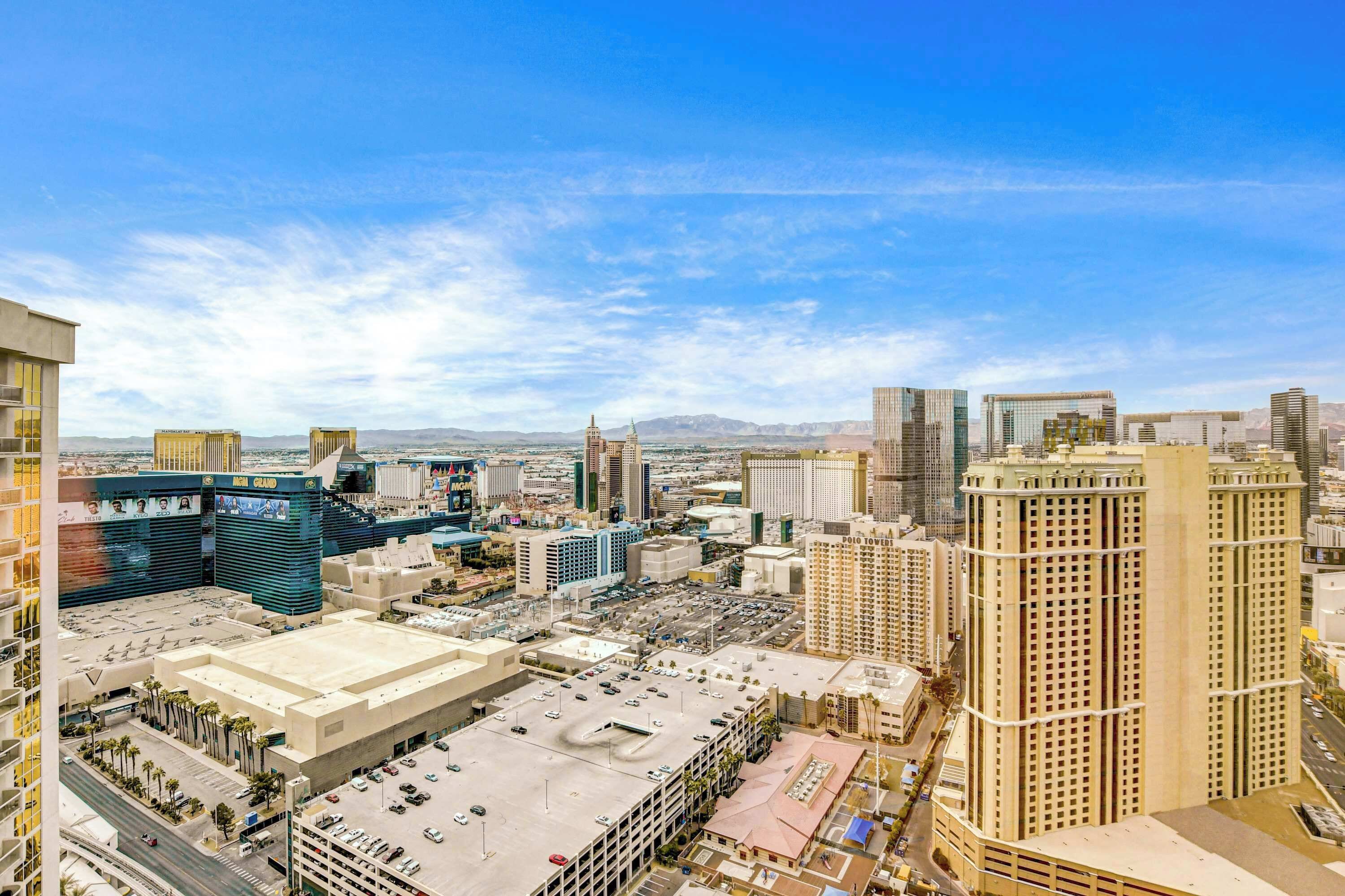 A high-rise hotel with a rooftop parking area, surrounded by other buildings and a clear sky.