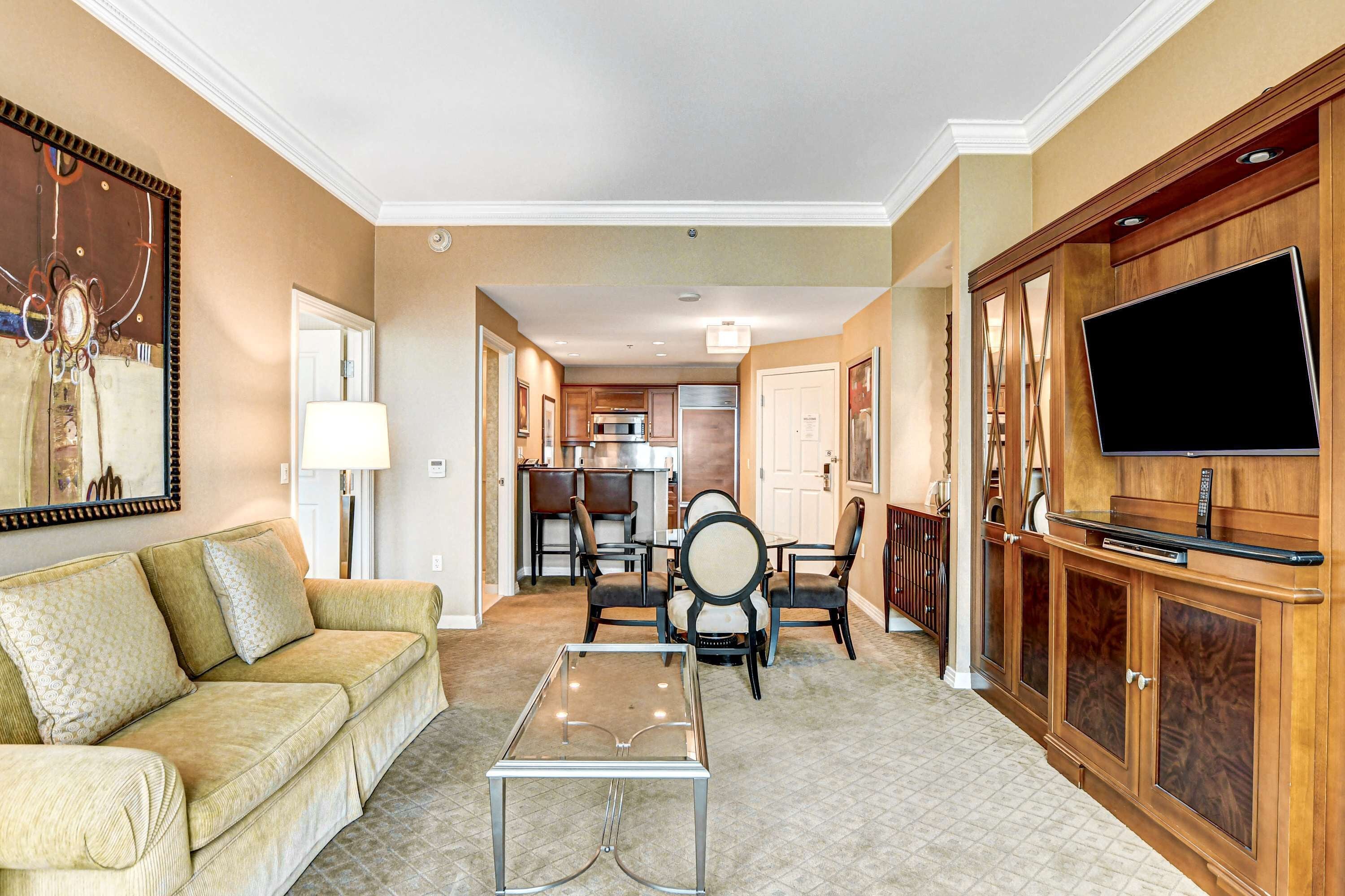 A living room with a sofa, chairs, a coffee table, and a TV on a wooden cabinet.