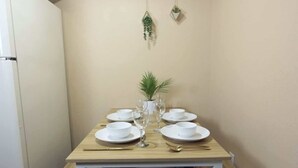 A dining table set with white plates, bowls, and cutlery, centered with a potted plant. - Calm Japandi Retreat With Patio, Near Downtown (Sarasota)