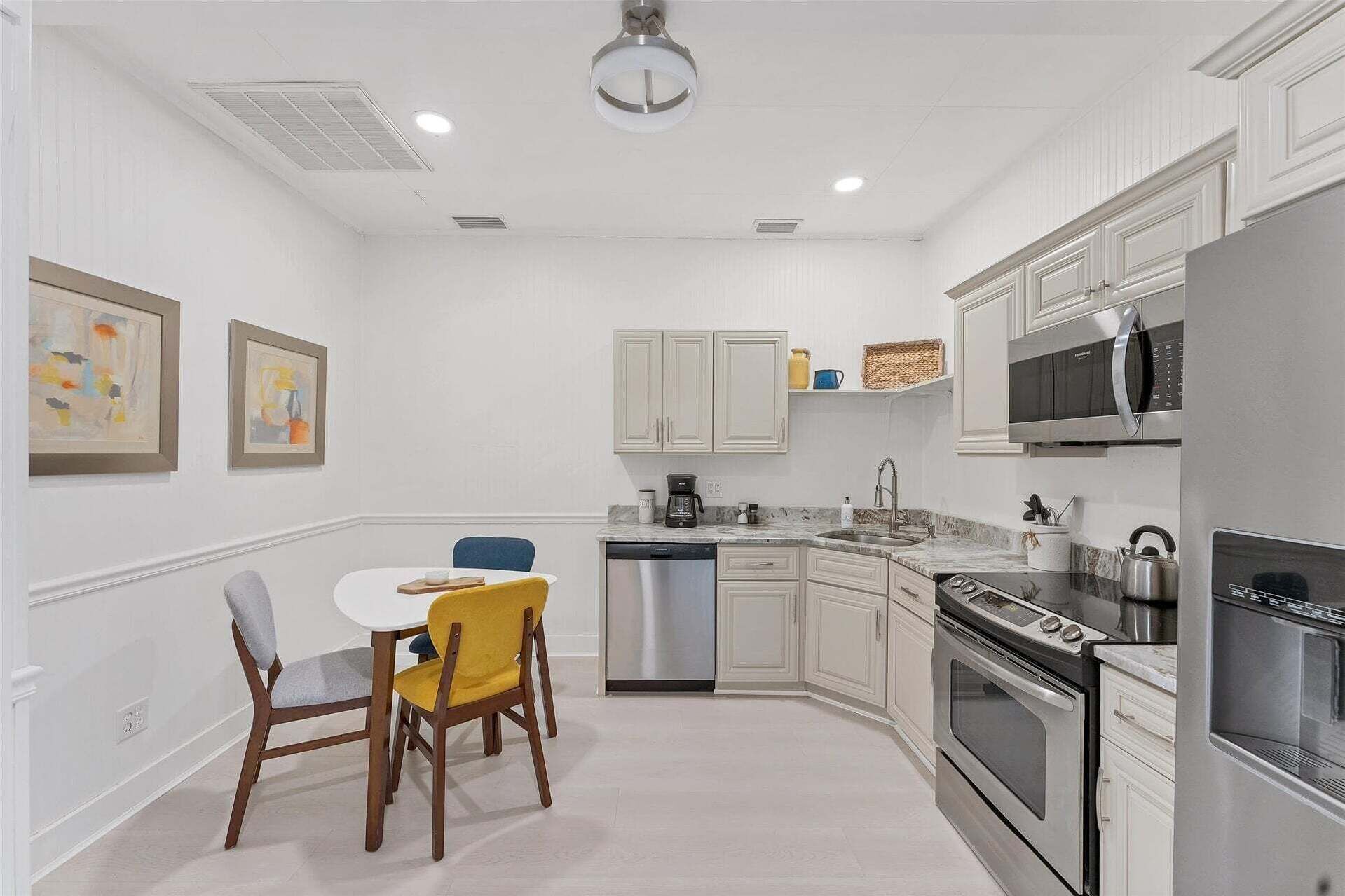 A modern kitchen with white cabinetry, a dishwasher, a stove, and a microwave.