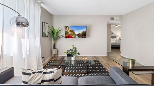 Ein modernes Wohnzimmer mit einer Couch, einem Couchtisch und einem an der Wand befestigten Fernseher.