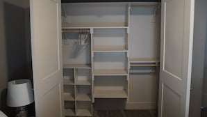 Um closet amplo com portas abertas, com várias prateleiras e espaço para pendurar roupas.