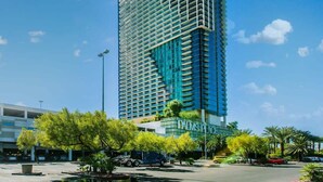 A tall, modern hotel building with a grid-like facade, surrounded by palm trees and a parking area. - Beautiful Strip-view Balcony Access Studio 31318 (Las Vegas)