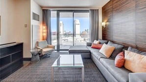 A modern hotel room with a large window, a sofa, a coffee table, and a TV. - Beautiful Strip-view Balcony Access Studio 31318 (Las Vegas)