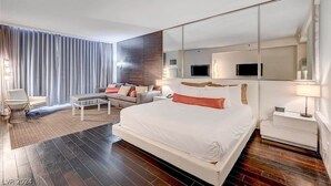 A modern hotel room with a large bed, a sofa, a coffee table, a TV, and a mirror. - Beautiful Strip-view Balcony Access Studio 31318 (Las Vegas)