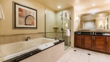 Un baño moderno con una bañera grande, ducha con cerramiento de vidrio y tocador de madera.