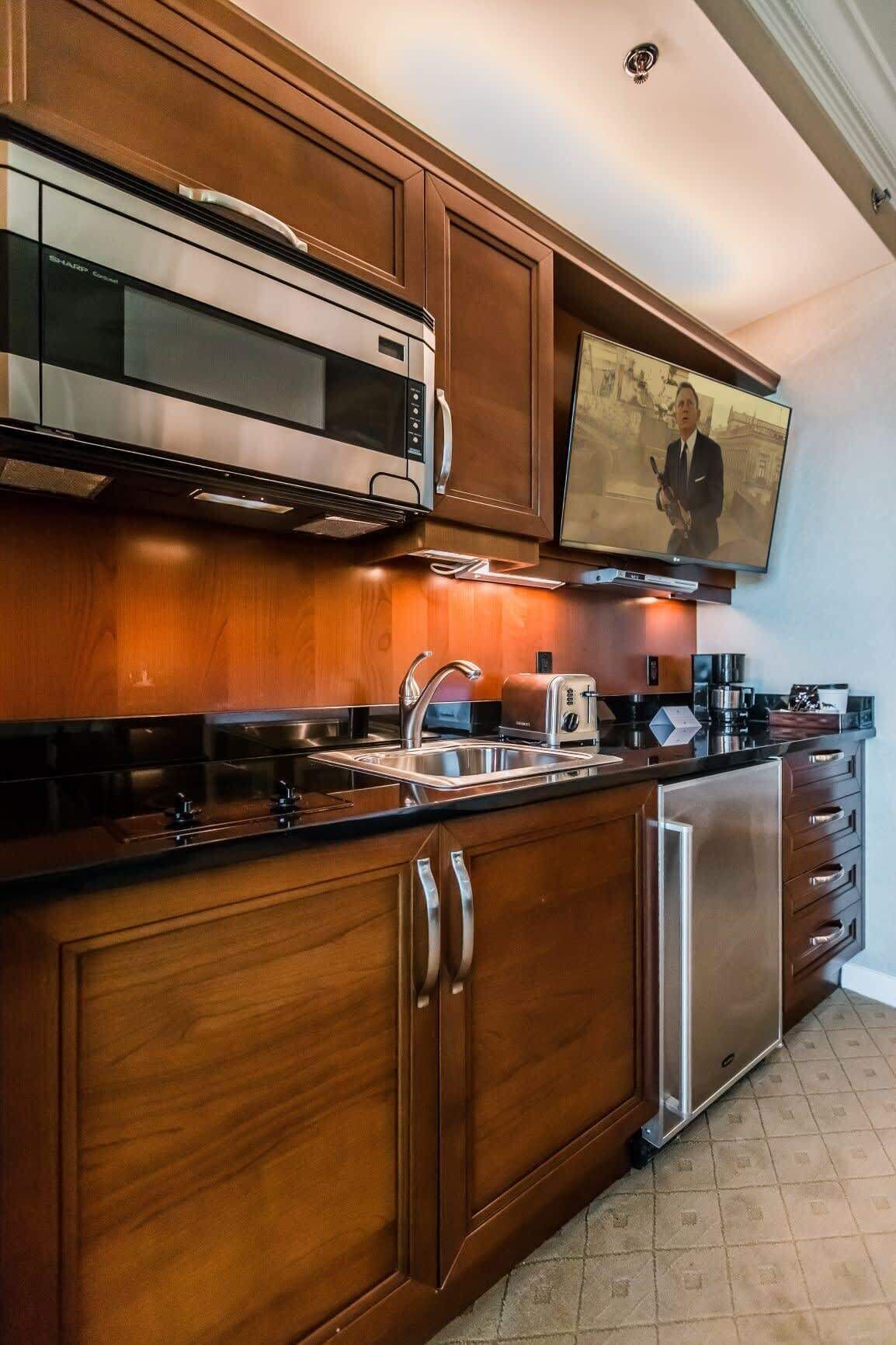 Una cocina con armarios de madera, electrodomésticos de acero inoxidable, horno empotrado, microondas, tostadora y refrigerador.