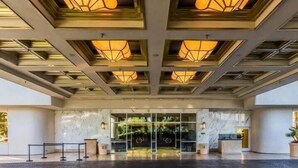 A hotel entrance with a modern design, featuring a marble reception desk and a glass door entrance. - Free Valet Parking MGM Studio 1911 (Las Vegas)