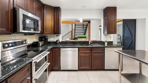 Una cucina moderna con mobili in legno scuro, elettrodomestici in acciaio inossidabile e un'isola centrale con lavello.