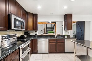 A modern kitchen with dark wood cabinets, stainless steel appliances, and a central island with a sink. - Extravagant Phoenix Retreat Pool Gazebo Heatedpool (Phoenix)