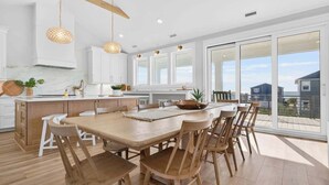 Una cocina moderna con una isla grande, armarios blancos y vistas al exterior.