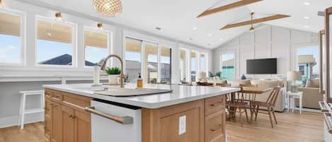 A spacious kitchen with wooden cabinets, a large island, pendant lighting, and a view of the outdoors.
