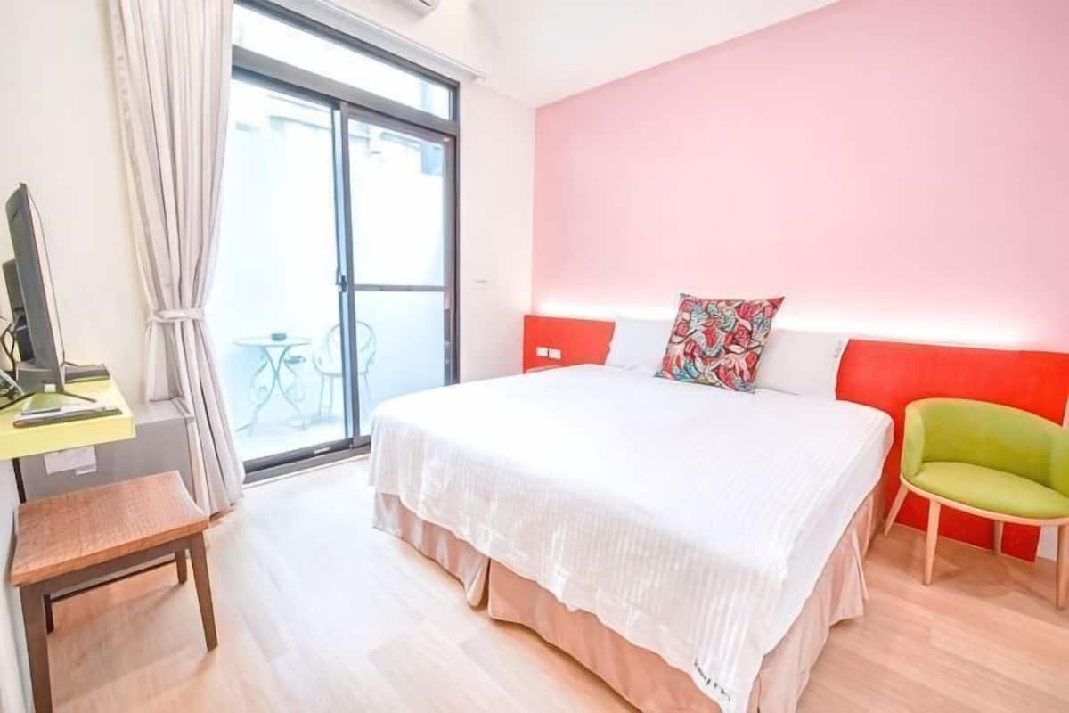 Ein Schlafzimmer mit Bett, Schreibtisch, Stuhl und einem Fenster mit Vorhängen.