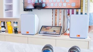 Une pièce avec un téléviseur fixé au mur, une tablette et deux haut-parleurs placés sur une étagère.