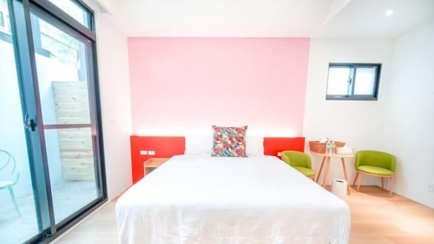 Une chambre avec un grand lit, une porte-fenêtre coulissante, une petite table avec des chaises et une fenêtre.