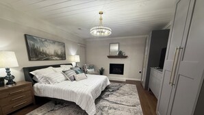 Una camera da letto con un letto, comodini, un lampadario, un camino e un armadio.