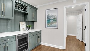 Una cucina con mobili grigi, una dispensa per vino e un quadro appeso al muro.